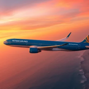 Airplane VN168 of Vietnam Airlines flying over Da Nang's coastline at sunset.